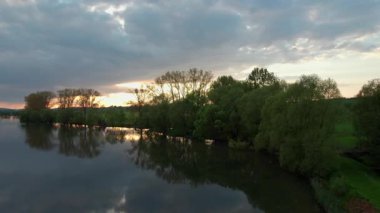 Tarlalarla çevrili samimi bir Alman köyünün yakınındaki gölün üzerinde büyüleyici bir günbatımı. Kuş bakışı görüş. Almanya.