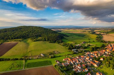 Büyüleyici Alman köyü, gür bir vadi boyunca yayılıyor, canlı çatıları ile mavi gökyüzünün altında, tüylü bulutlarla süslenmiş manzarayı noktalıyor. Doğa her yönde gelişir. Almanya.