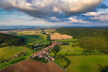 Büyüleyici Alman köyü, gür bir vadi boyunca yayılıyor, canlı çatıları ile mavi gökyüzünün altında, tüylü bulutlarla süslenmiş manzarayı noktalıyor. Doğa her yönde gelişir. Almanya.