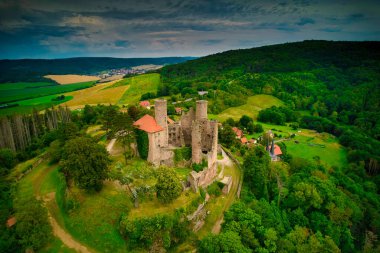Görkemli yeşil tarlalar ve görkemli manzaralar arasında zarif bir şekilde yerleşmiş tarihi bir kalenin çarpıcı bir şekilde ele geçirilmesi. Hanstein Kalesi, Almanya.
