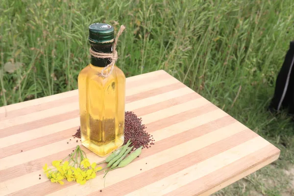 mustard oil in bottle with flower and bud and seed on farm for harvest are cash crops