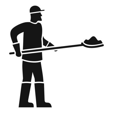 İnşaat işçisi çizme ve eldiven giyip elinde kürekle inşaat malzemesi tutuyor.