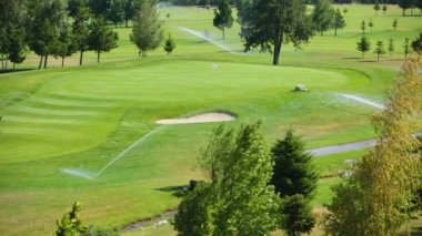Bulgaristan 'daki yeşil golf sahasında yüksek basınçlı su fıskiyesi çimenleri suluyor.
