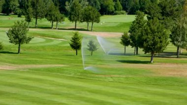 Bulgaristan 'daki yeşil golf sahasında yüksek basınçlı su fıskiyesi çimenleri suluyor.