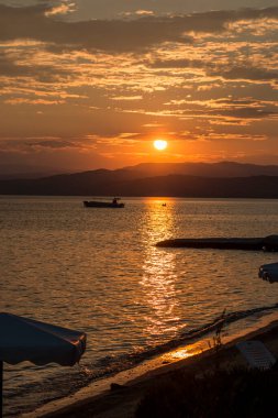 Ege Denizi 'ndeki adaların üzerinde dramatik bir günbatımı gökyüzü, kameraya güneş ışığı. Arkaplan veya duvar kağıdı için fikir. Denizde nefes kesici gün batımı, tatil zamanı.