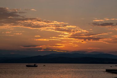 Ege Denizi 'ndeki adaların üzerinde dramatik bir günbatımı gökyüzü, kameraya güneş ışığı. Arkaplan veya duvar kağıdı için fikir. Denizde nefes kesici gün batımı, tatil zamanı.