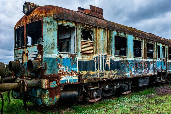老旧生锈的客车电动多单元列车退役 被遗弃在绿草地里的铁路边沿上 图库照片