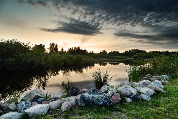 风景秀丽的日落映照在风景如画的湖面上 天空和云彩映照在水面上 岩石和石头映衬在前方 图库图片