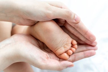Yeni doğan bebeğin ayakları annenin ellerindedir. Anne ve bebek kavramı yakın plan.