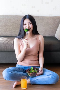 Hayat tarzı güzel güzel bir kadın Asyalı tatlı bir kız diyet yemeğinden zevk alıyor. Sabahları sağlıklı olmak için taze salata ve portakal suyu yiyor.
