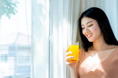 Lifestyle beautiful beauty woman Asian cute girl feel happy enjoy eating diet food , drinking orange juice for good health in the morning