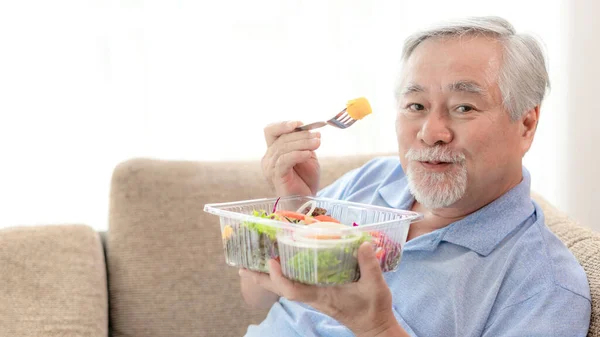 노인은 소파에서 샐러드를 먹는다 — 스톡 사진