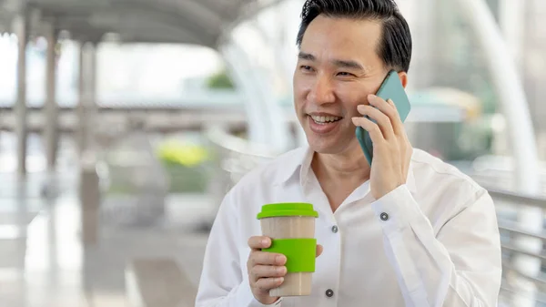 Επιτυχημένος Ασιάτης Επιχειρηματίας Που Χρησιμοποιεί Έξυπνο Τηλέφωνο Και Φλιτζάνι Καφέ Εικόνα Αρχείου