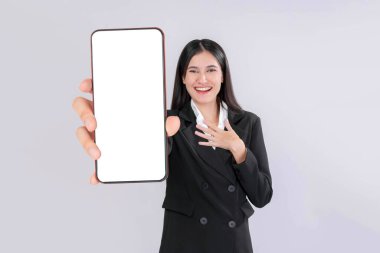 Siyah takım elbiseli profesyonel Asyalı iş kadını elinde beyaz ekranlı akıllı bir telefon tutuyor, teknolojiyi, iş hizmetlerini ve dijital ürünleri destekliyor, gri arka planda izole edilmiş.