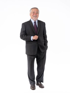 Kendine güvenen koyu takım elbiseli kıdemli bir işadamı, bir eli ceketinde, diğer eli cebinde, beyaz arka planda, liderliği sembolize eden, başarıyı simgeleyen profesyonel bir duruş sergiliyor.