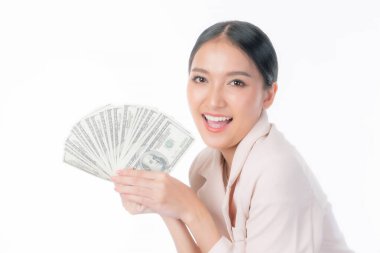 Heyecanlı, açık pembe takım elbiseli Asyalı iş kadını elinde ABD dolarlarının hayranı, başarı ve finansal özgürlüğü ifade eden, iş ve para kavramları için beyaz bir arka planda izole edilmiş,