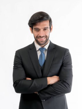 Kendine güvenen siyah takım elbiseli, mavi kravatlı, kollarını kavuşturup gülümseyen, beyaz arka planda izole edilmiş, şirket portresi ve profesyonel başarı kavramı olan genç iş adamı.