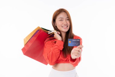 Uzun kahverengi saçlı, neşeli bir Asyalı kadın elinde renkli alışveriş çantaları ve bir kredi kartı, beyaz bir arka planda parlak bir gülümseme, alışveriş çılgınlığına hazır.