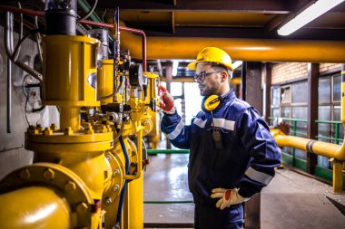 Natural gas power plant worker checking energy production inside factory.
