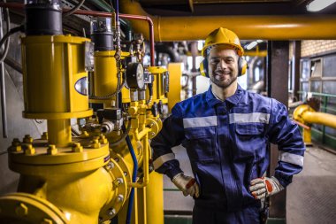 Portrait of technician standing inside heating plant boiler department.