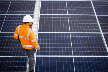 Engineer walking through large solar energy power plant.