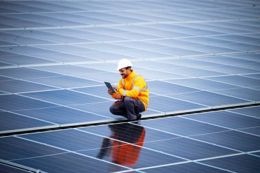 Dizüstü bilgisayarlı profesyonel işçi güneş enerjisi santralinin elektrik üretimini kontrol ediyor.