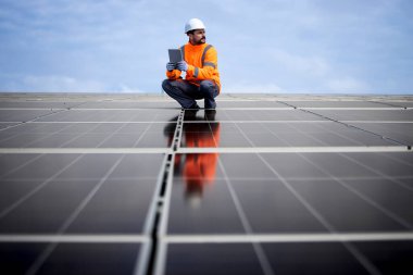 Professional worker with digital tablet controlling electricity production of solar power plant.