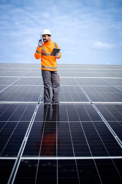 Portrait of solar power plant engineer with laptop computer controlling sustainable energy production.