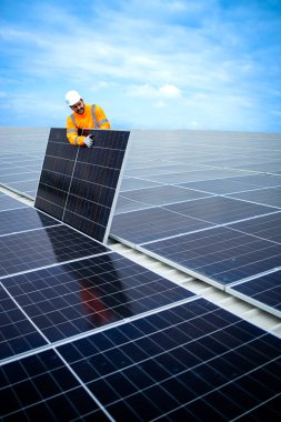 Installing solar power plant as sustainable energy source. Worker placing solar panel on the roof.
