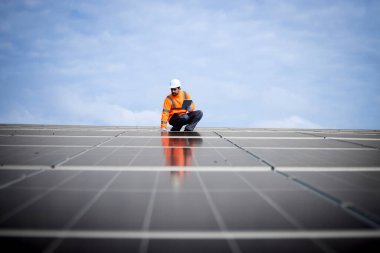 Solar energy worker or engineer with his laptop computer checking installation and productivity of new solar power plant.