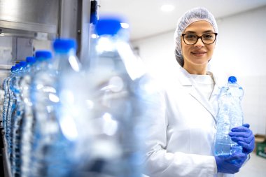 Portrait of experienced caucasian female employee working in bottling factory production line. clipart