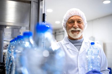 Portrait of an experienced man worker in white sterile coat standing in food and bottling factory.
