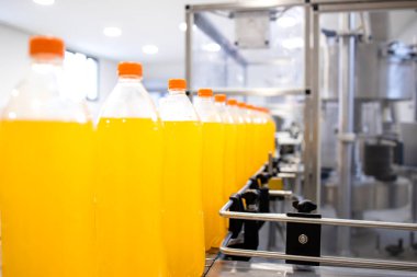 Bottled orange juice being produced on conveyor belt machine.