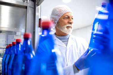 Factory supervisor checking product quality in bottling plant.