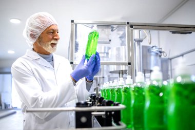 Experienced technologist controlling production of sanitation chemicals inside detergent factory.