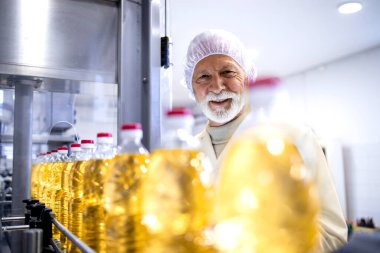 Experienced technologist controlling process of vegetable oil production in food factory.