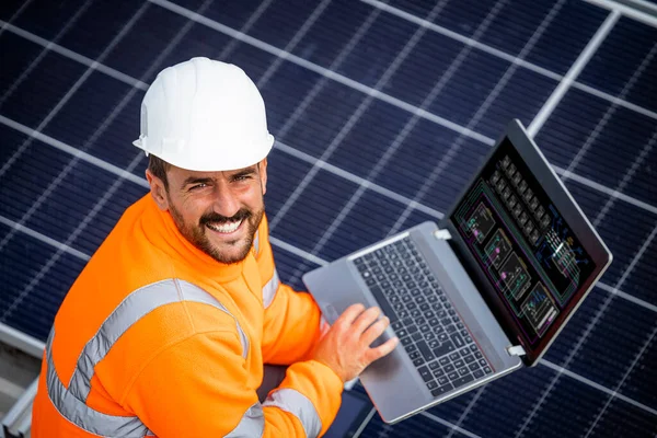 Solar panels installation for sustainable energy. Electrical engineer holding laptop computer with solar panels scheme and checking productivity.