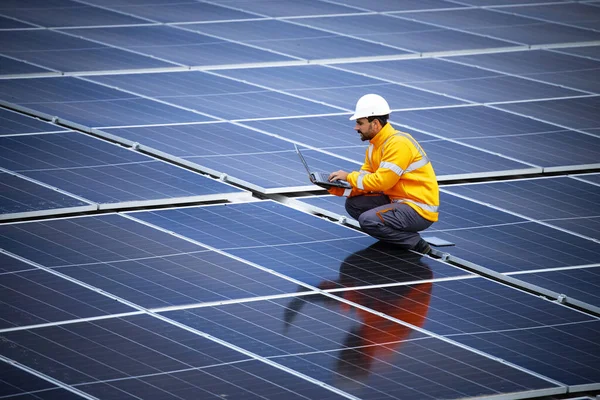 stock image Solar energy plant engineer standing between photovoltaic panels and checking electricity production for industry.