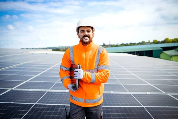 Portrait of solar energy worker with arms crossed standing in solar power plant.