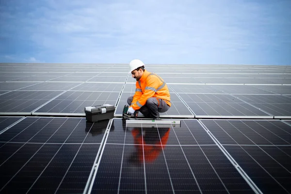 Hardworking employee mounting photovoltaic solar panels. Sustainable energy source.