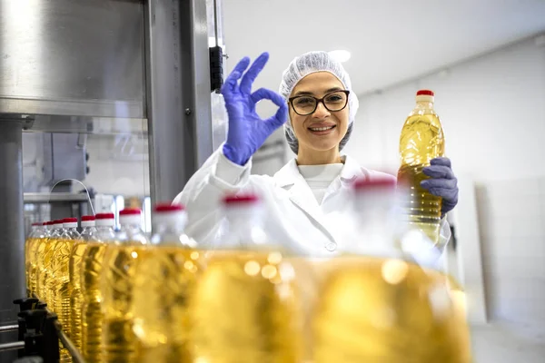 Portrait of female technologist inside food production factory approving quality of refined vegetable oil products.