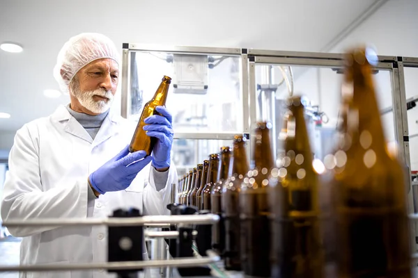 ビール製造工場と経験豊富な労働者が充填する前にガラス瓶をチェック — ストック写真