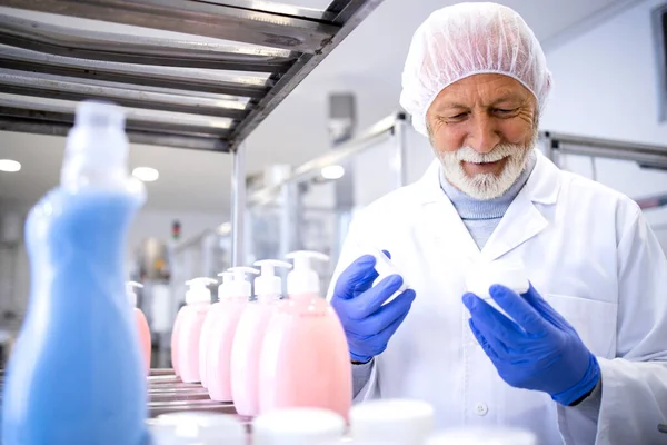 化粧品工場内でアンチエイジングクリームの品質をテストする経験豊富な製薬労働者 — ストック写真
