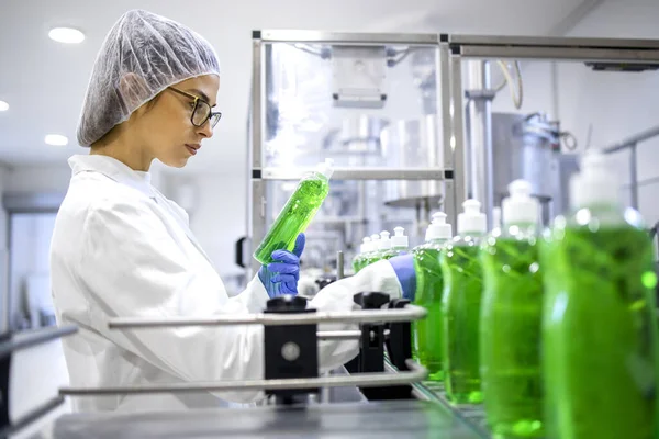 Female technologist controlling production of cleaning supplies or sanitation chemicals for cleaning industry. Checking quality of detergent.