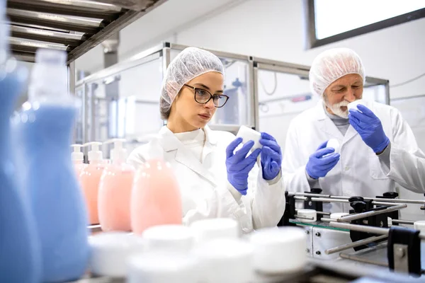 Pharmaceutical workers controlling production of anti-age cream and testing quality.