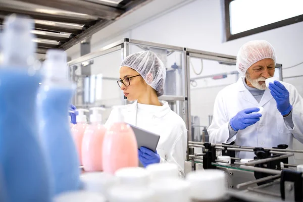 Employees working together in pharmaceutical factory and controlling production of cosmetics products.