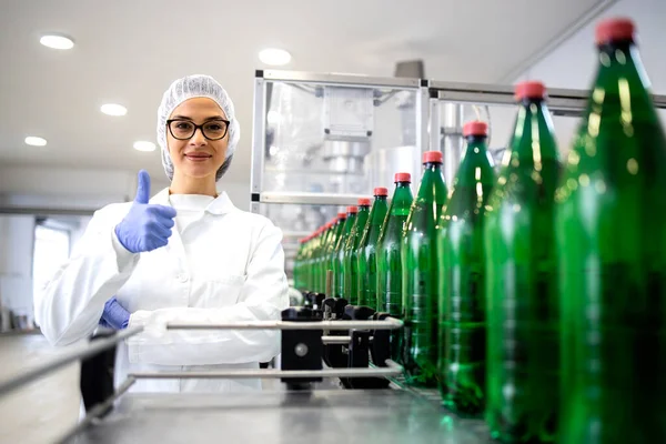 女性技術者が親指を立てて工場で飲料製造に成功したことを表します — ストック写真