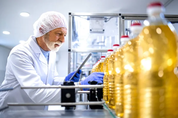 植物油ボトリング工場で働く食品業界の専門家は 生産プロセスを制御します — ストック写真