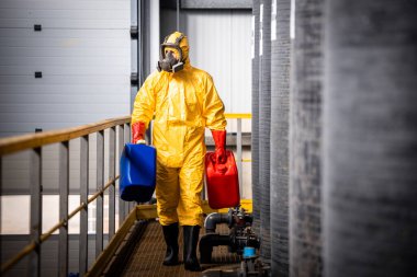 Koruyucu giysi ve gaz maskeli endüstriyel işçiler plastik kutular ve kimyasallar taşıyorlar..
