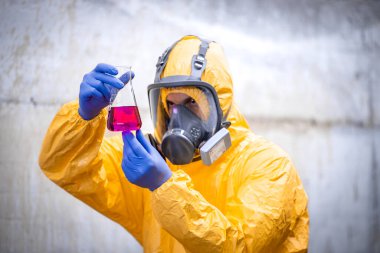 Chemical testing laboratory. Worker in special equipment and gas mask testing quality.